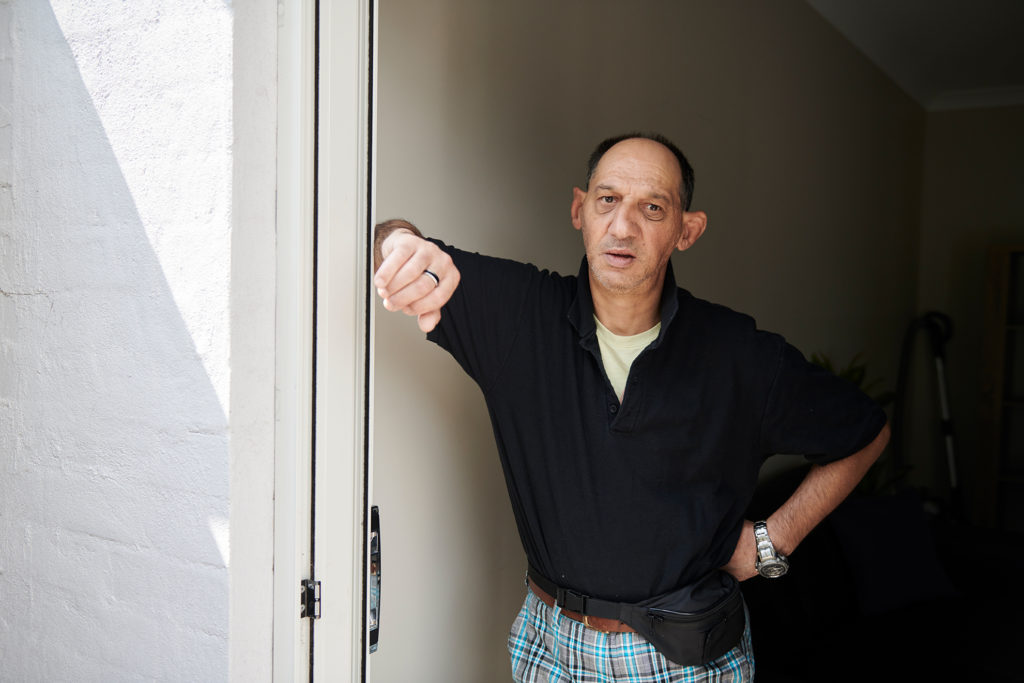 Man in black t-shirt leaning against a door