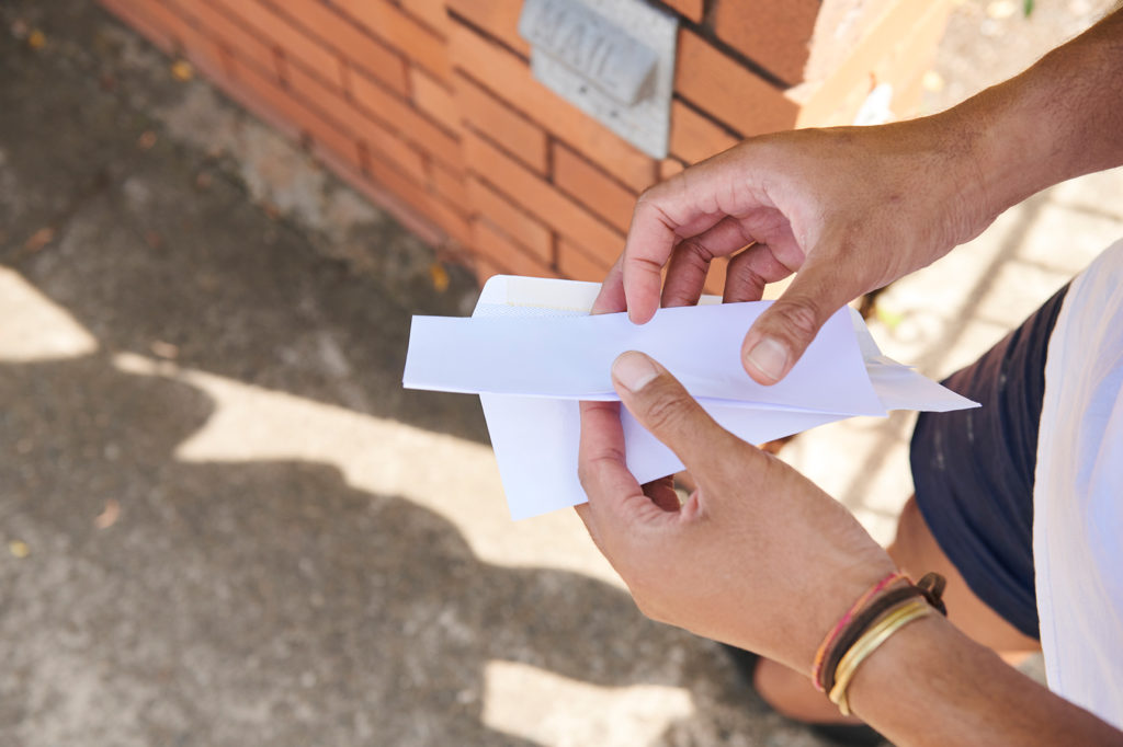 Guy's hands opening letter outside