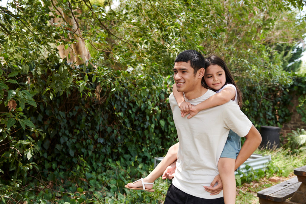Youth piggybacking girl in garden