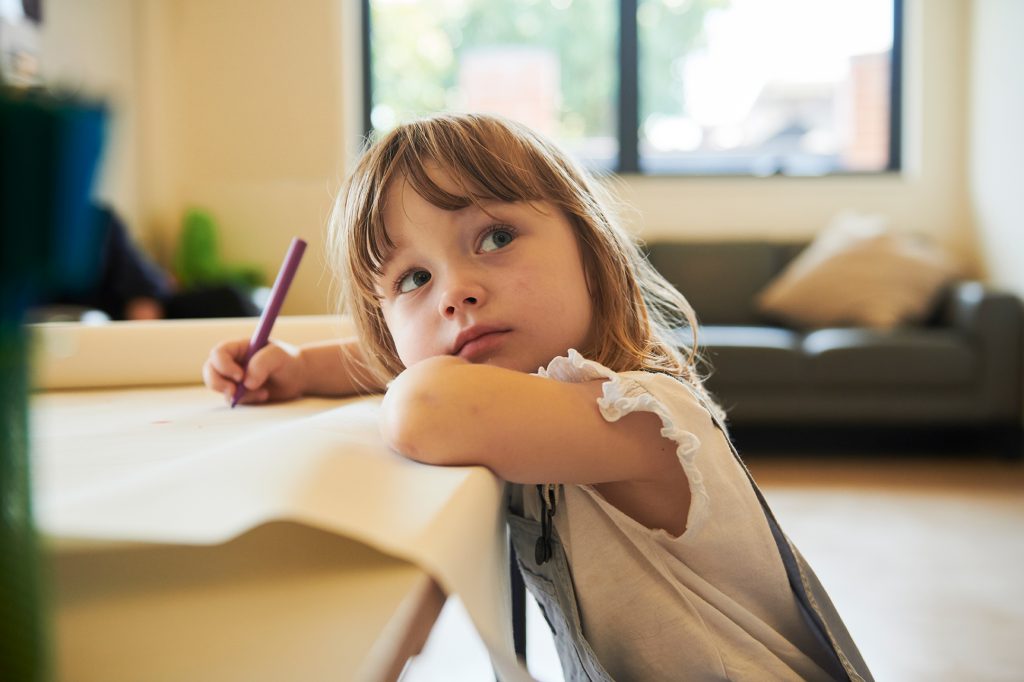 Toddler in overalls drawing with pen