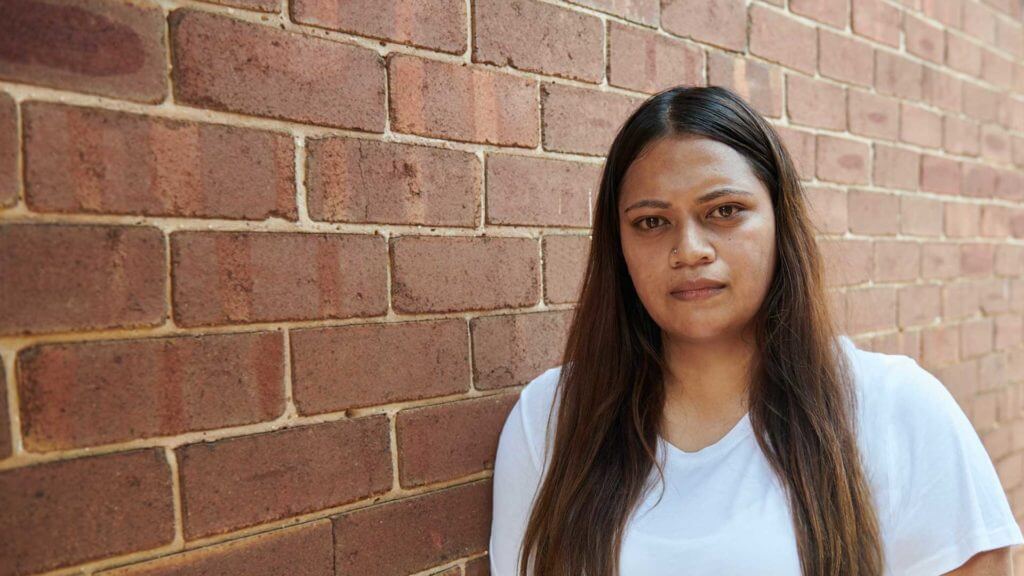 girl standing next to brick wall