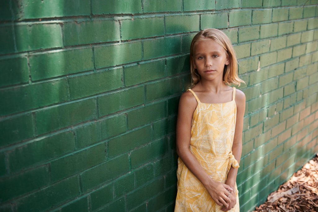 Young girl next to wall