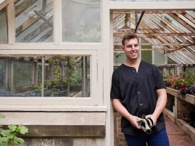 man standing next to greenhouse