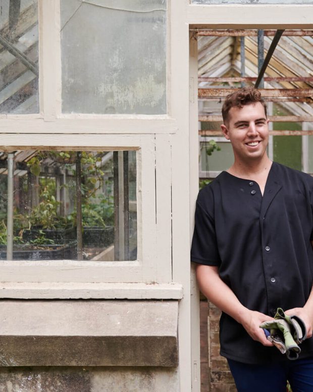 man standing next to greenhouse