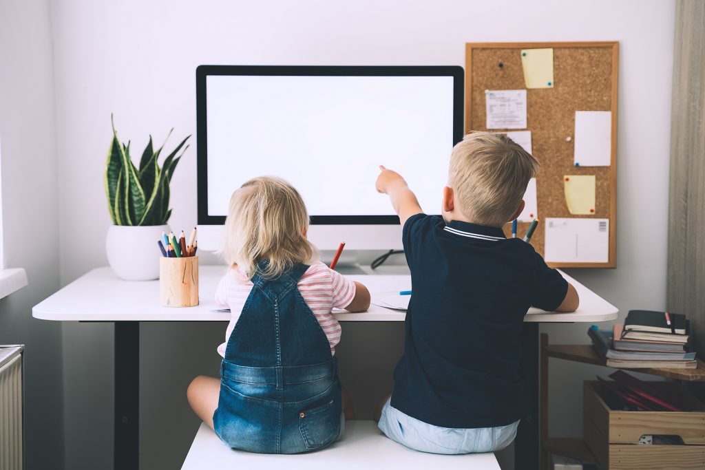 Little Boy And Girl Sitting At Working Desk With Computer