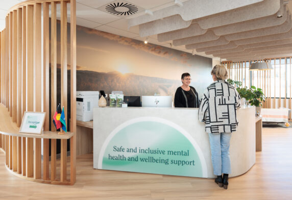 Women at the front of a Medicare Mental Health Centre desk, talking to worker