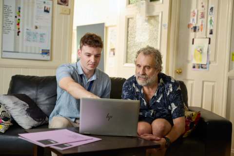 Stride support worker, pointing at screen, sitting with Stride participant