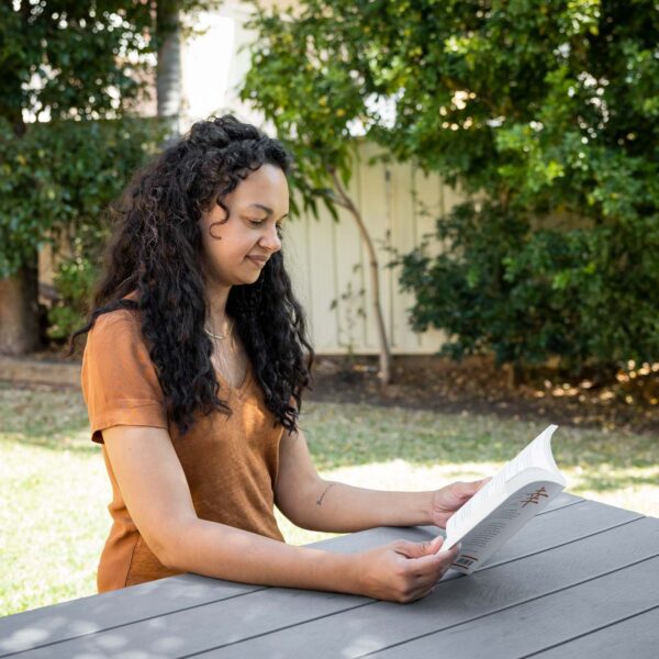 Lady in orange shirt, sitting on park bench reading