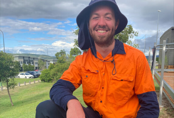 Alex smiles at the camera in his work gear