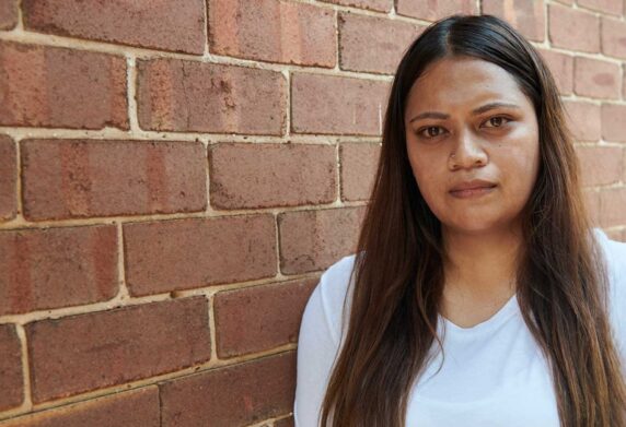 Woman standing in front of brick wall looking at camera