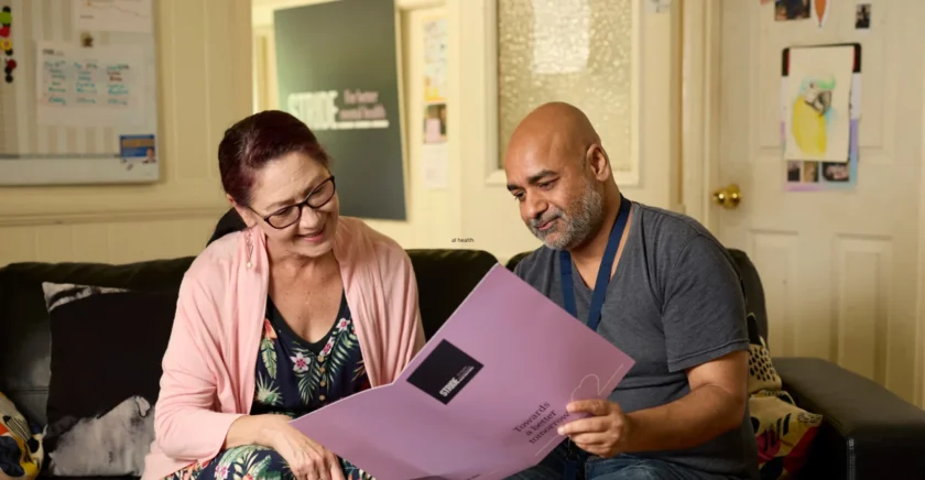 Woman and man sitting on lounge, pointing to Stride handbook
