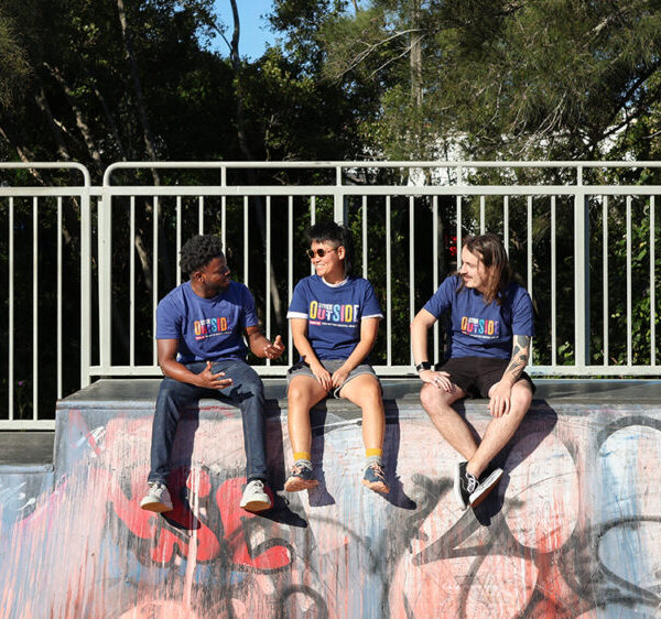 Stride Outside participants sit on the edge of a half-pipe laughing and chatting