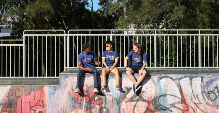 Stride Outside participants sit on the edge of a half-pipe laughing and chatting