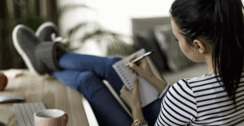 Woman sitting on chair writing in notebook