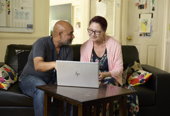 Support worker and client looking at a laptop together