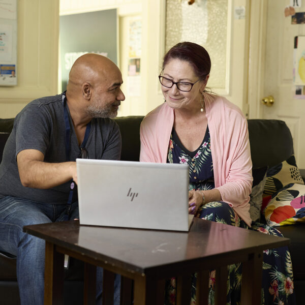 Support worker and client looking at a laptop together