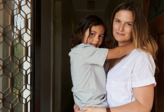 Mum holding daughter, smiling in doorway