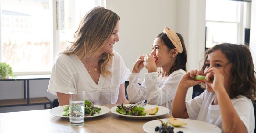 Mother and two kids sitting at table eating apples