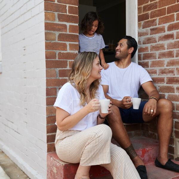 Mum dad and child sitting on house's front steps talking to each other