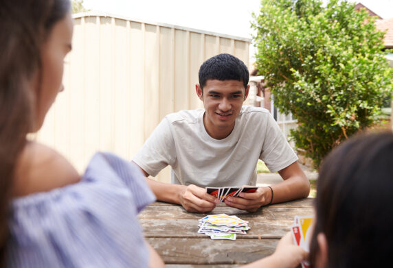 Young people playing cards in a backyard
