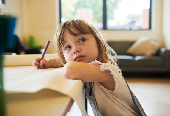 Small girl drawing and looking up next to camera