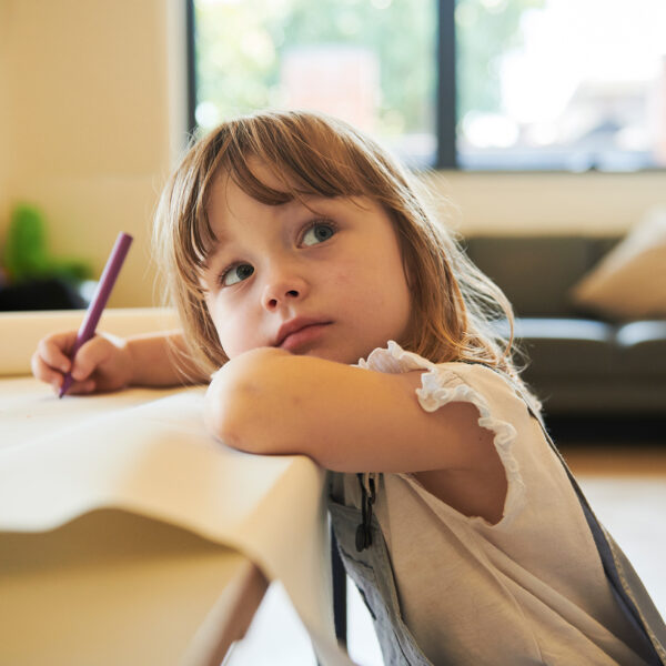 Small girl drawing and looking up next to camera