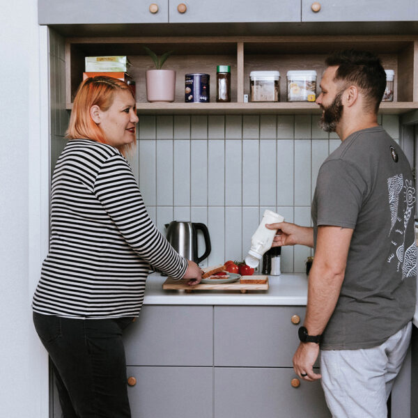 Two adults chatting while making sandwiches in a kitchen