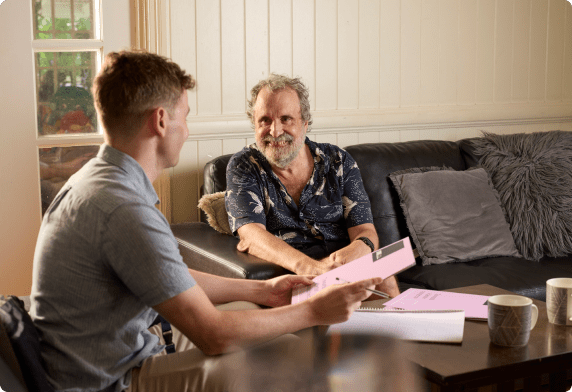 Two men sitting on the lounge looking at Stride pamphlet