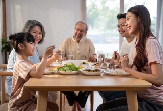 Family of 5 sitting around eating smiling and laughing together