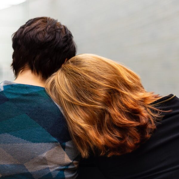 Man sitting next to woman with head on his shoulder