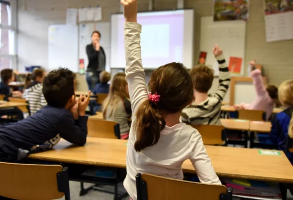 Kids in classroom with raised hand