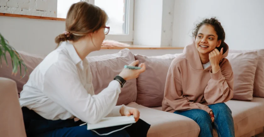 Young girl and young women sitting on lounge smiling and talking