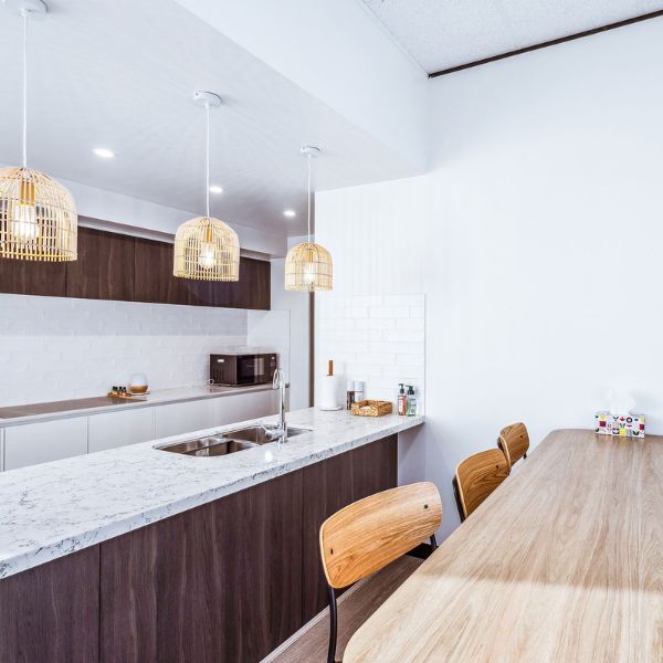 Kitchen area of dark mahogany wood and light counter top with big dining table