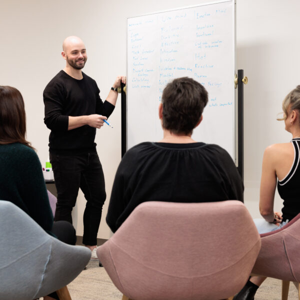 Person smiling at whiteboard with staff members gathered around
