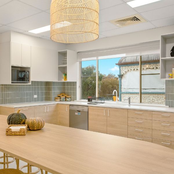 Kitchen area with light wooden oak, darker green tiles and natural light