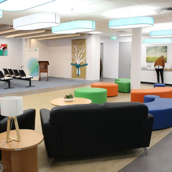Colourful seating area in foyer with black lounge and person grabbing coffee or tea