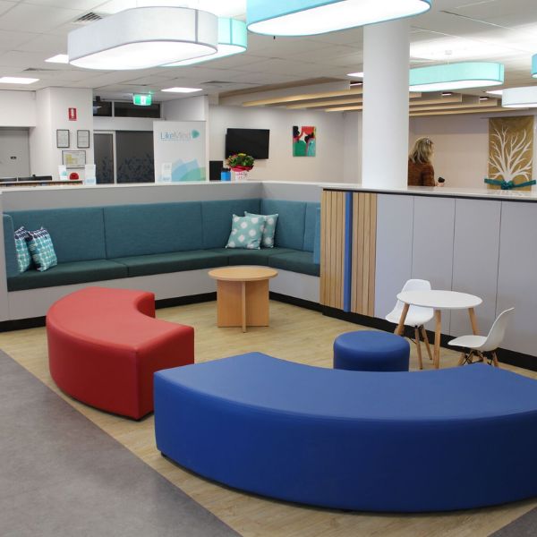 Colourful seating area in foyer with build in wall seats and reception area