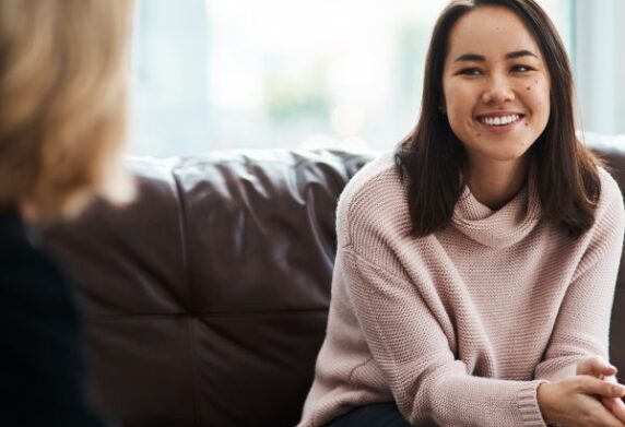 2 People sitting on brown couch having a pleasant conversation