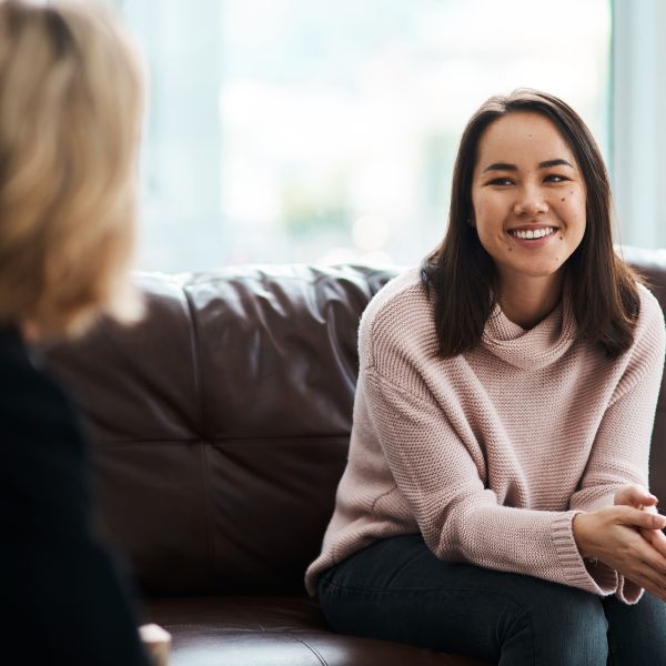 2 People sitting on brown couch having a pleasant conversation