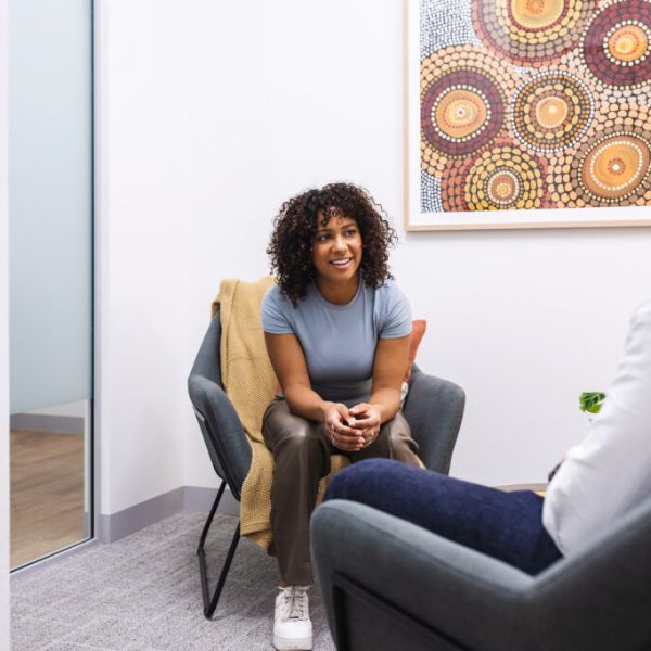 Two people having a conversation in consultation room with blankets and chairs
