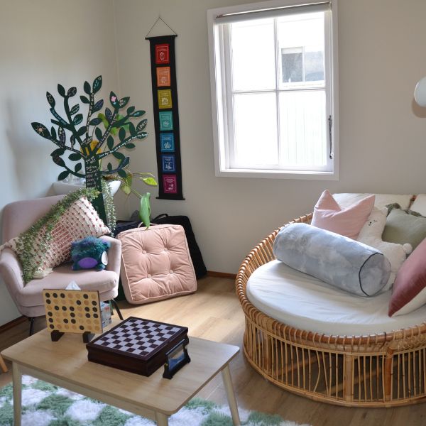 Comfortable large cream and rattan lounge chair in a calm space with plush pink chair, pillows and games