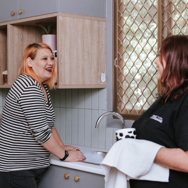Two people at kitchen sink chatting and laughing