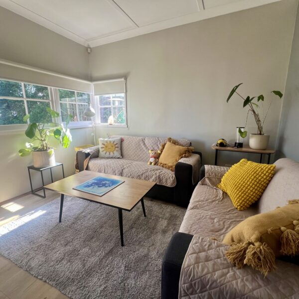 Well-lit room with greenery and two lounges with yellow/mustard coloured cushions