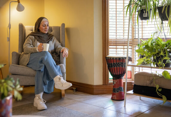 A lady sits in a cosy room drinking tea and resting