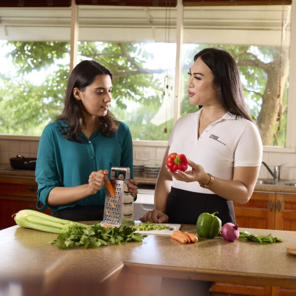 Two people at kitchen counter chatting over cutting vegetables to cook
