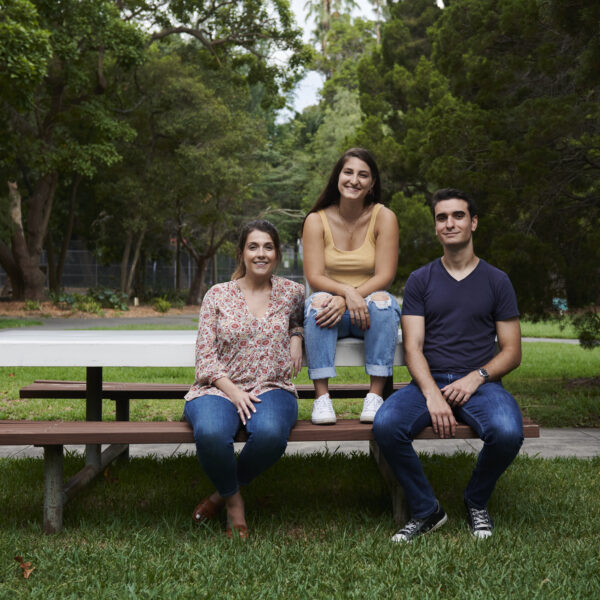 three youth people on park table and chair together smiling at camera