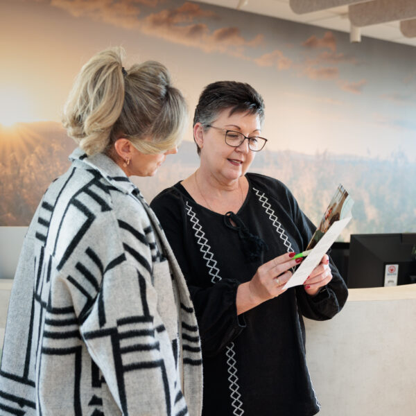 Two people at reception looking at clipboard with paperwork