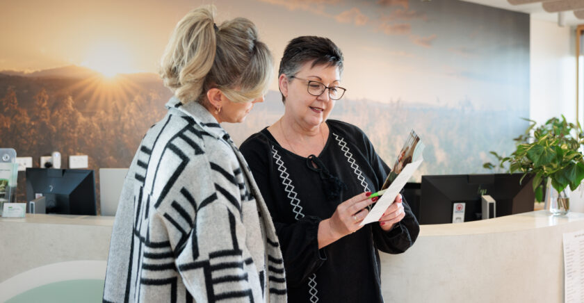 Two people at reception looking at clipboard with paperwork