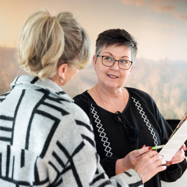 Two people smiling in discussion over a paperwork