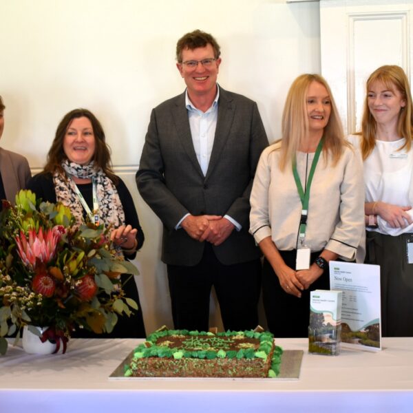 Stride team alongside Politician Andrew gee at a table with a Mental Health Month themed cake